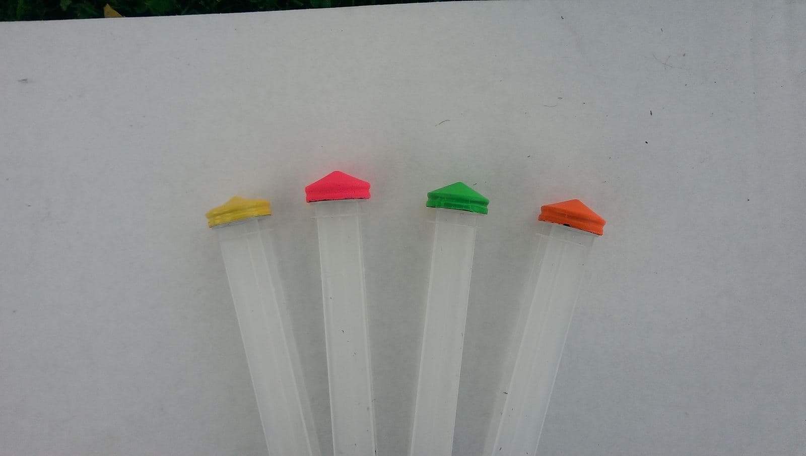 Early prototype syringes on a work surface, with fluorescent colored plunger seals next to a conventional black seal.