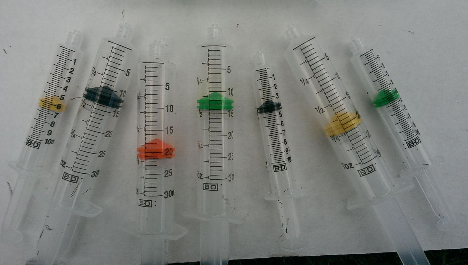 Early prototype syringes with fluorescent pink and green plunger seals.